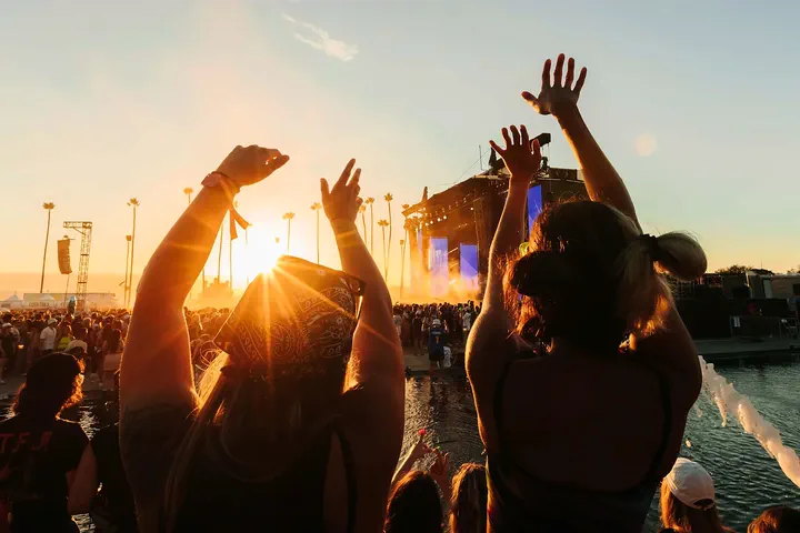 Festival guests raising their hands during a sunset performance