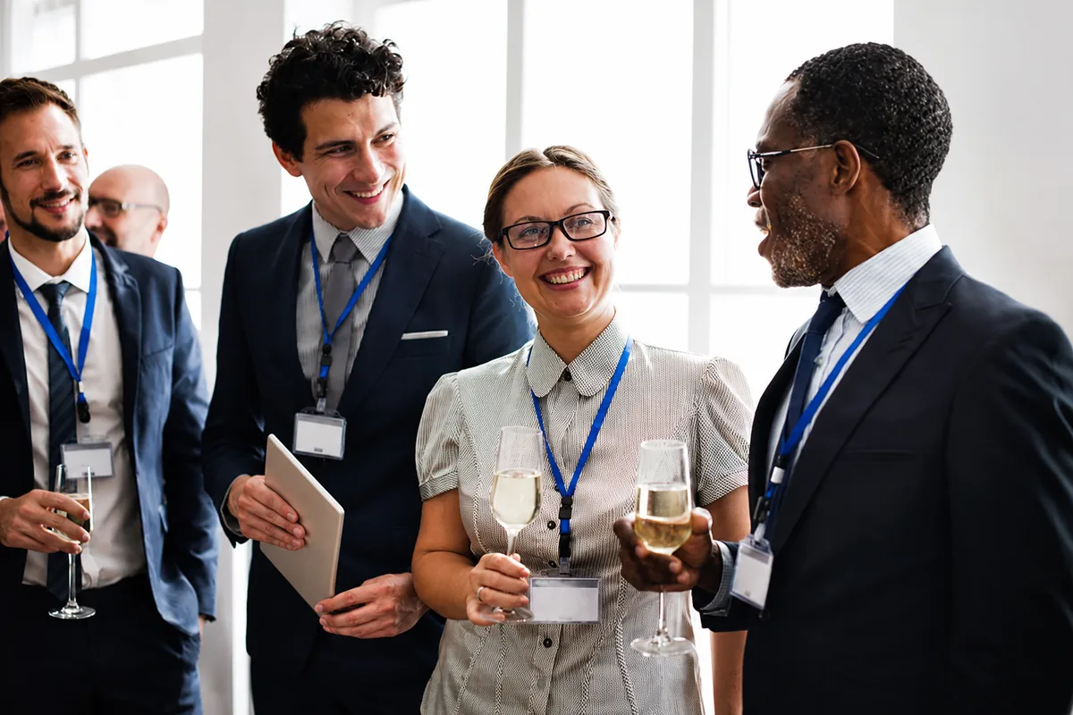 Conference attendees wearing badges talking together at a professional networking event